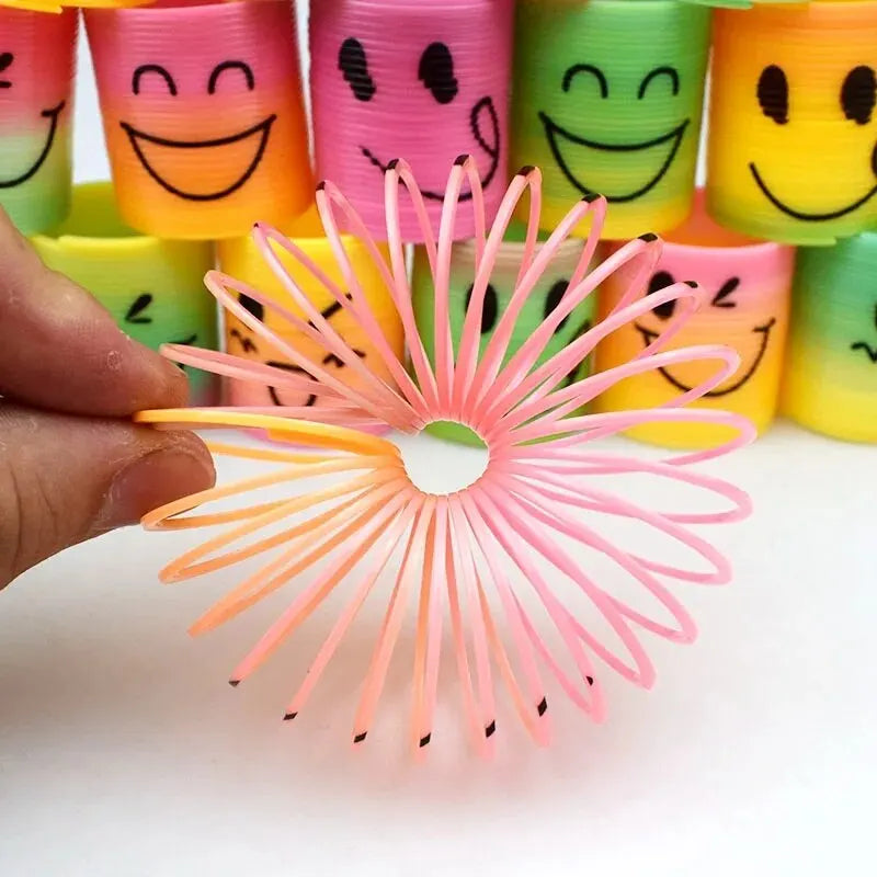 A hand holds a pink rainbow stacking circle toy set with multiple colors and a flower-like design.