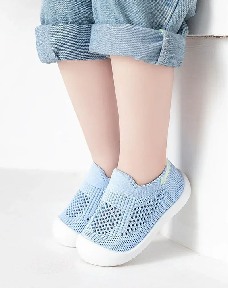 A pair of light blue breathable mesh slip-on sneakers for toddlers resting on a white surface.