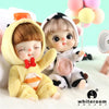 A pair of soft, fluffy mini dolls with facial features and poseable joints sitting on a white surface.