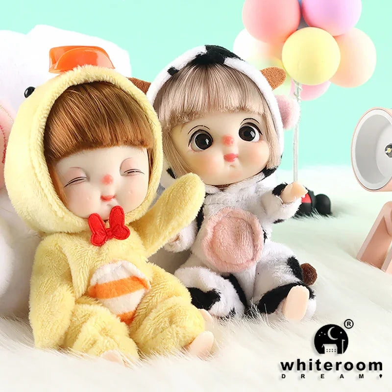 A pair of soft, fluffy mini dolls with facial features and poseable joints sitting on a white surface.