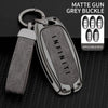 A matte grey buckle key case cover with a silver metal loop and multiple applicable keys displayed on a black textured surfac