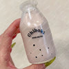 A clear glass bottle filled with pink liquid labeled Chiboki drink cup toy being held in a hand.
