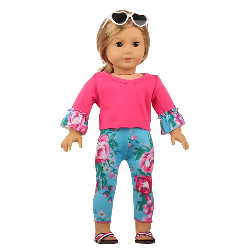 A doll wearing a pink unicorn pajama set with floral print leggings and sunglasses.