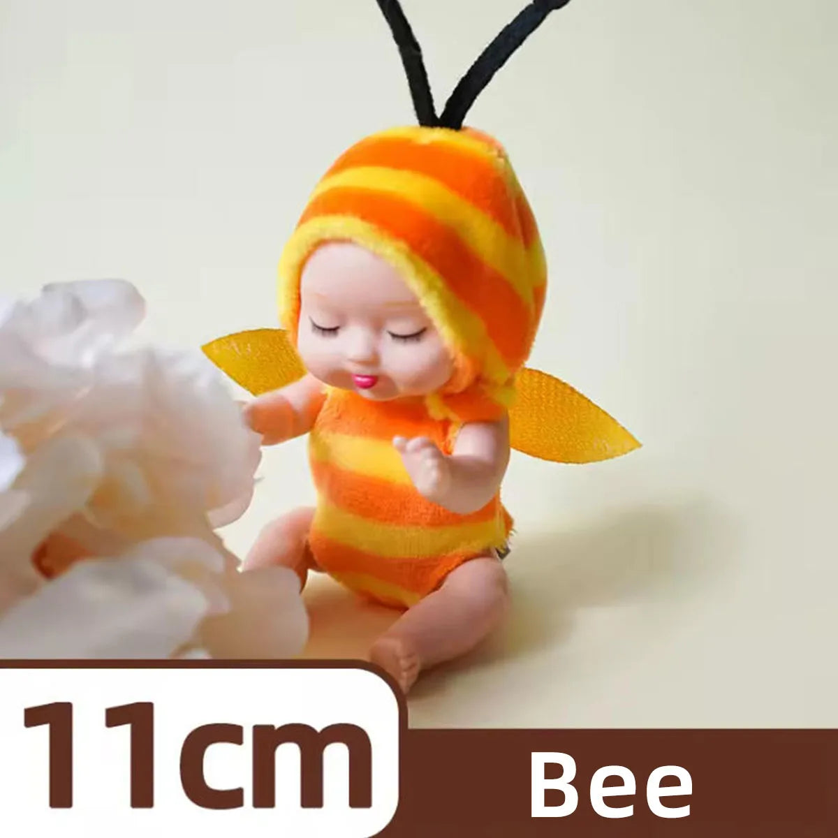 A small reborn baby doll with an orange and yellow striped hood and yellow wings.