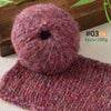 A ball of deep magenta alpaca blend yarn next to a knitted swatch.