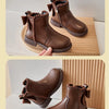 A pair of brown ankle boots for girls featuring a bow-knot detail and a side zipper, shown in a studio setting.