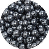 A close-up view of small, dark gray imitation pearl beads scattered in a pile.