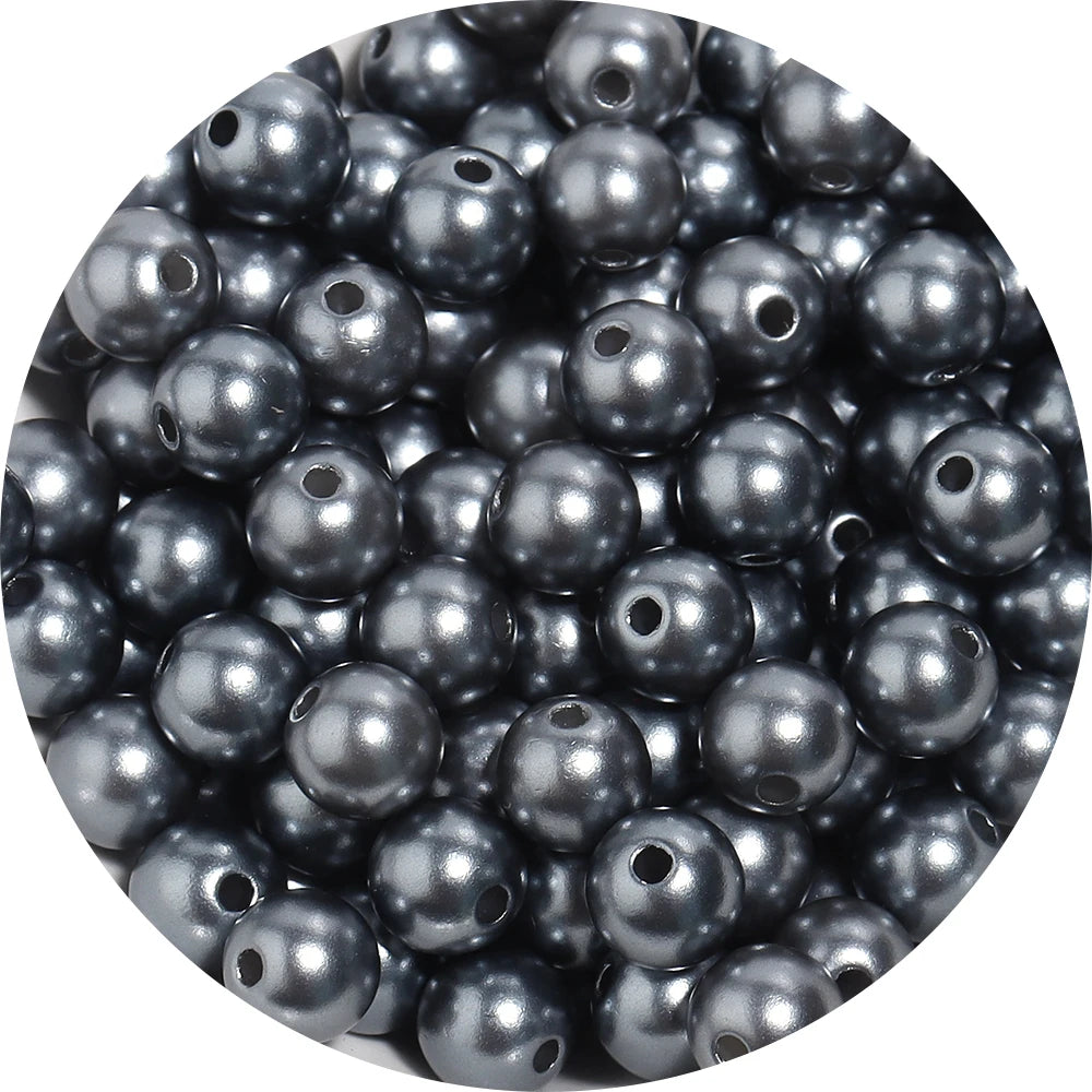 A close-up view of small, dark gray imitation pearl beads scattered in a pile.