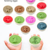 A collection of dinosaur pair twisting eggs in various colors, including pink, red, green, and blue, shown next to hands.