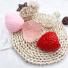Pink and red strawberry squishy fidget toys with various textures and a woven mat