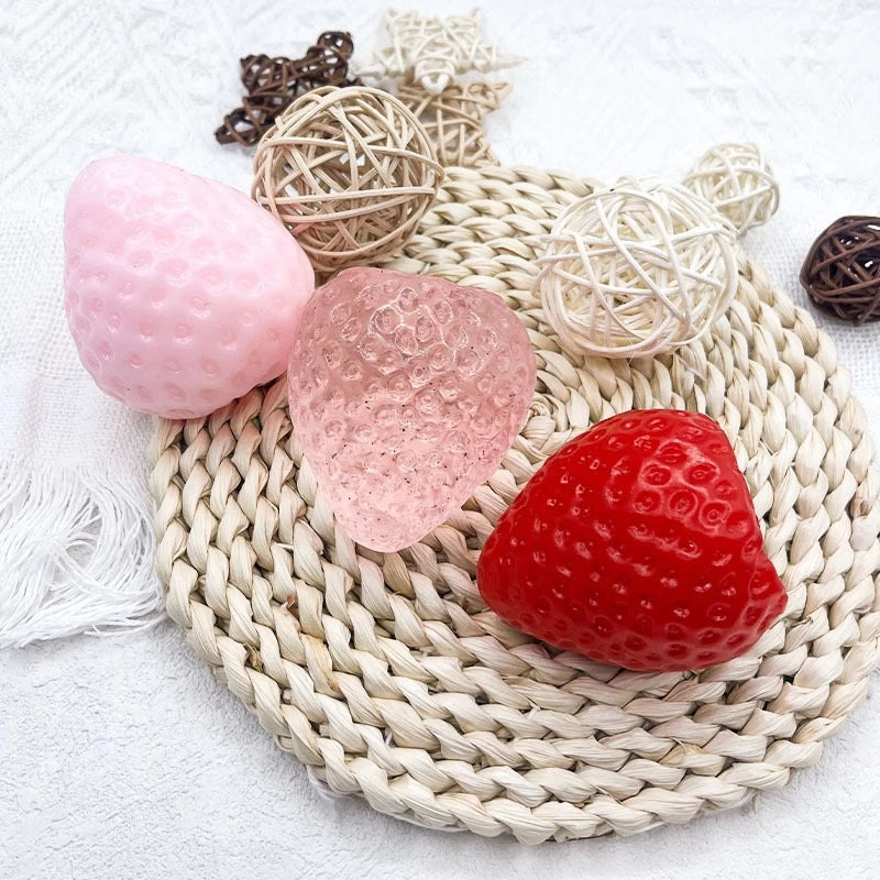 Pink and red strawberry squishy fidget toys with various textures and a woven mat