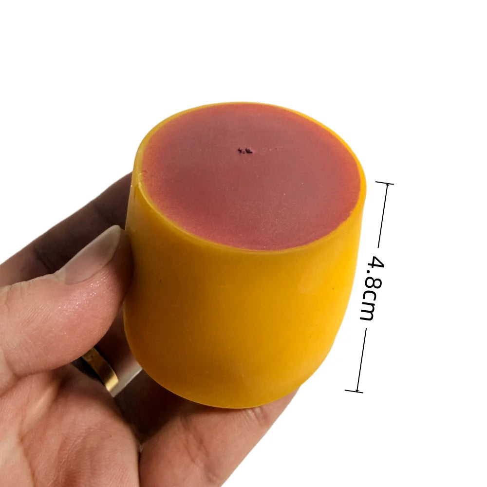 A hand holds a round, squishy stress ball with a yellow outer layer and a pink inner layer.