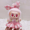 A cute doll wearing a pink and red plaid outfit with a matching bow and fluffy pink hair.