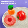 A set of colorful plastic food items including a green and orange bottle and a red tomato on a white surface.