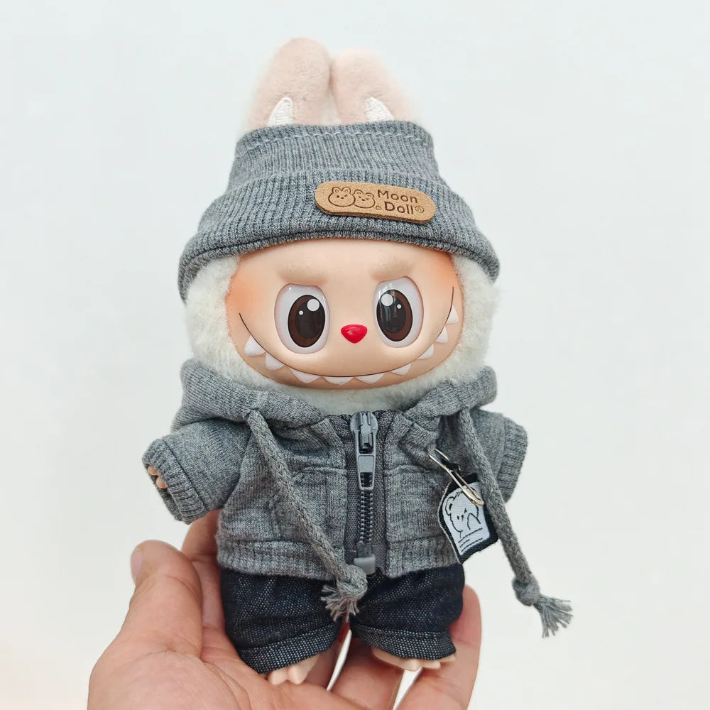 A Labubu doll wearing a grey hoodie and hat with white ears, held in a hand.
