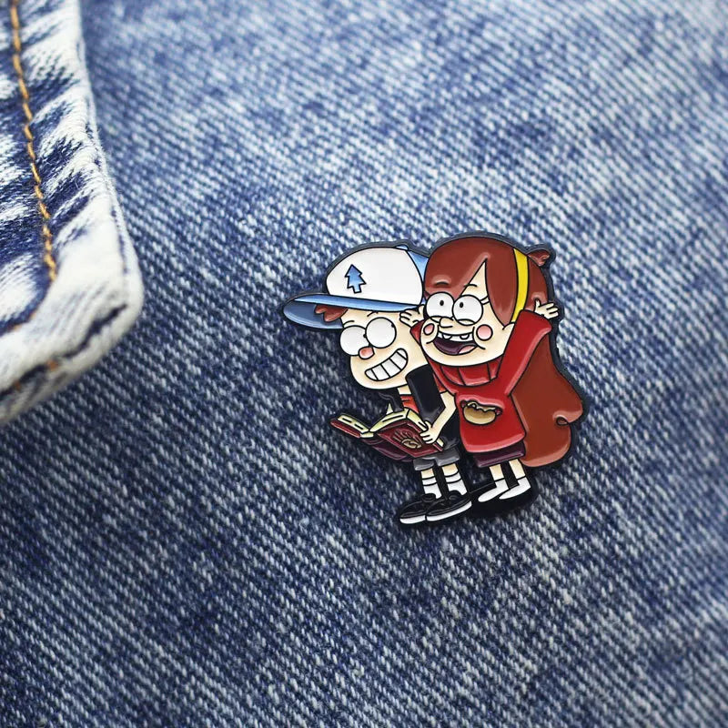 Enamel pin set featuring a boy and girl character from Gravity Falls wearing baseball caps and jackets