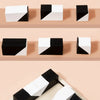 Un ensemble de blocs de construction en bois géométriques noir et blanc, de différentes formes et couleurs.