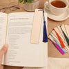A page from a book showing blank wooden bookmarks with tassels next to a cup of tea.