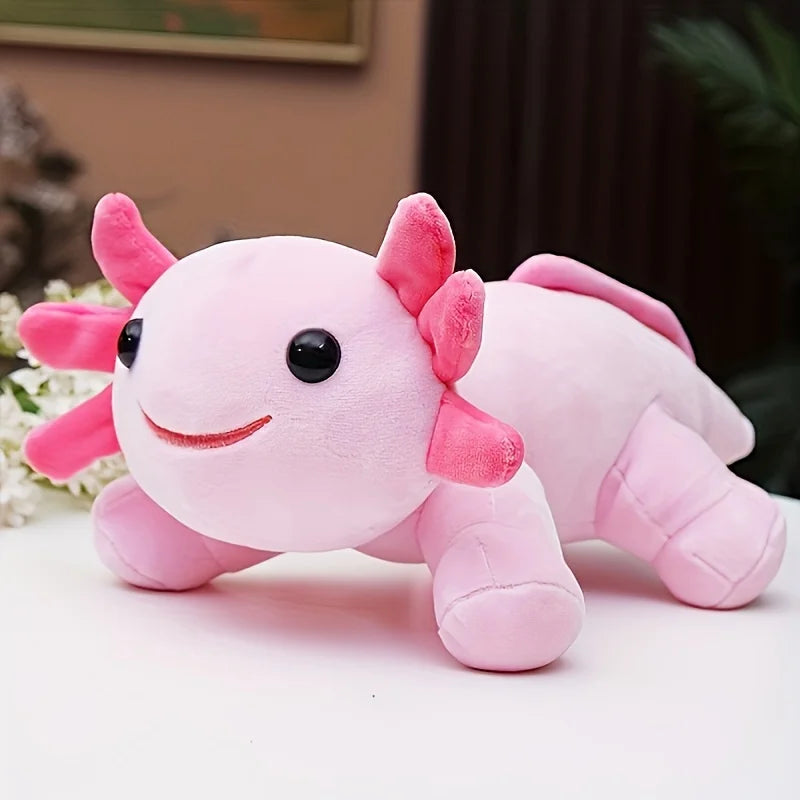 A soft pink axolotl plush toy with pink gills and a black eye is shown on a white surface.