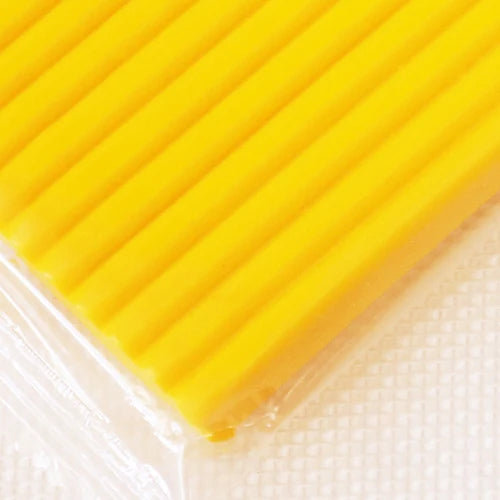 A bright yellow block of soft modeling clay is visible, packaged in clear plastic.