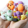 A hand holds a collection of colorful squishy toys shaped like various animals and characters for stress relief.