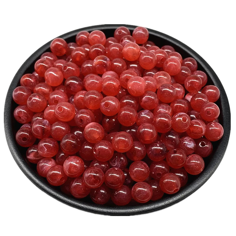 A pile of translucent reddish-pink acrylic round beads for jewelry making.