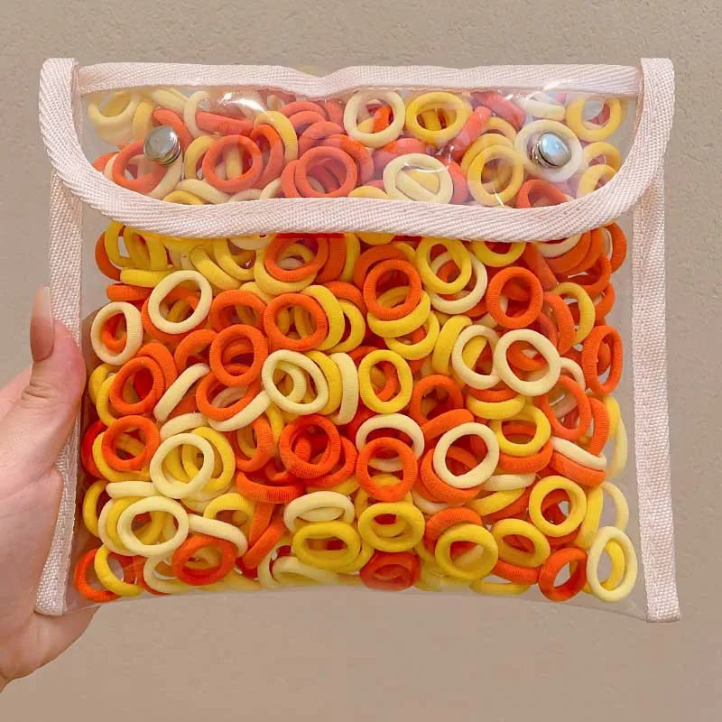 A clear plastic bag filled with colorful nylon hair ties in orange, yellow, and white.