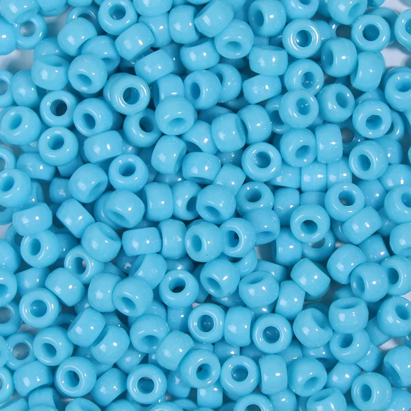 A pile of small, round, light blue pony beads for jewelry making and craft projects.