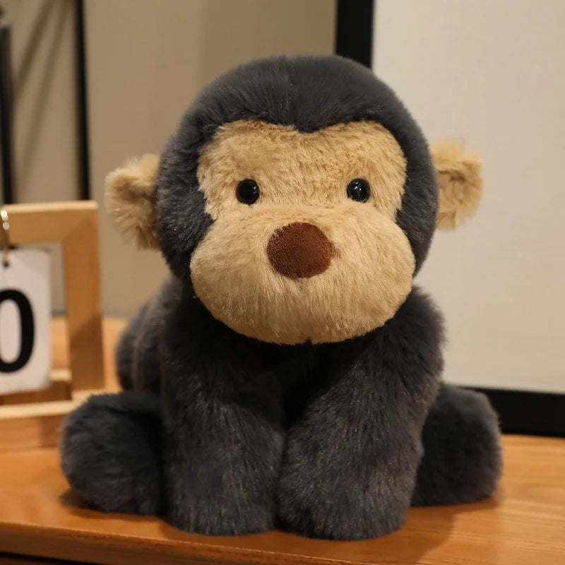 A gray plush monkey soft toy with light brown accents sitting on a wooden surface.