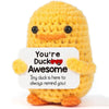 A handmade crochet yellow duck doll with orange feet and a text card that reads You're Ducking Awesome
