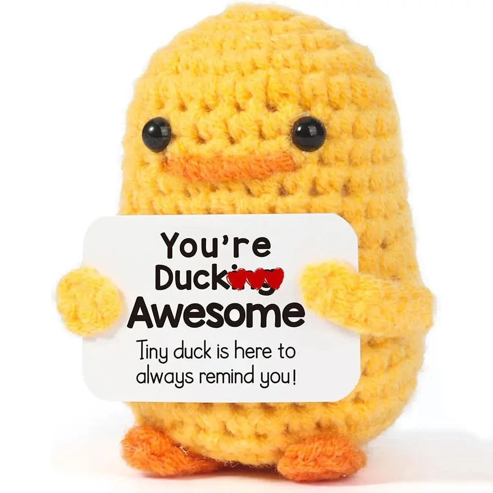 A handmade crochet yellow duck doll with orange feet and a text card that reads You're Ducking Awesome