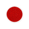 A clear container filled with bright red round glass seed beads for jewelry making.