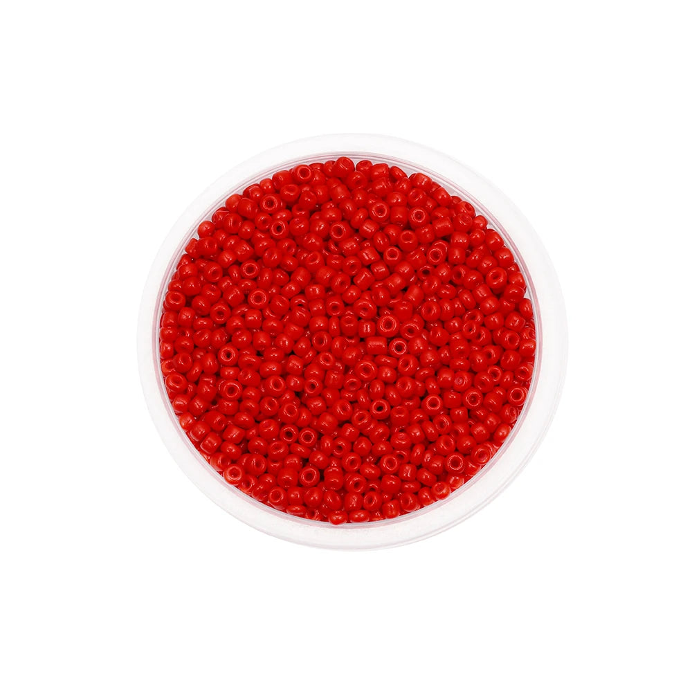 A clear container filled with bright red round glass seed beads for jewelry making.