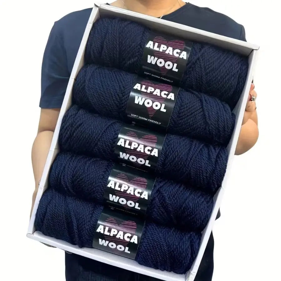 A pack of five dark navy alpaca wool yarns displayed in a white frame.