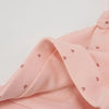 A soft pink baby hat with a gathered knot detail and small heart patterns.