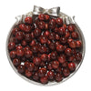 A pile of dark reddish-brown, round resin beads for jewelry making displayed in a silver dish.