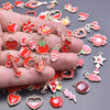 A hand holds an assortment of gold-tone enamel charms featuring hearts, flowers, strawberries, and stars for jewelry making.