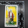 A tarot card titled The Magician featuring a figure standing before tools and elements on a yellow background.