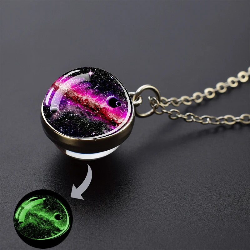 A pendant necklace featuring a glow-in-the-dark image of a nebula and planets on a dark background.