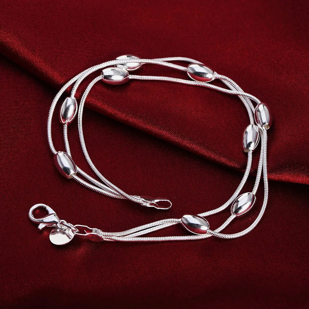 Elegant sterling silver snake chain bracelet for women displayed on a dark red velvet fabric.