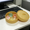 A yellow steamer basket containing five translucent squishy toys in various colors on a white desk.