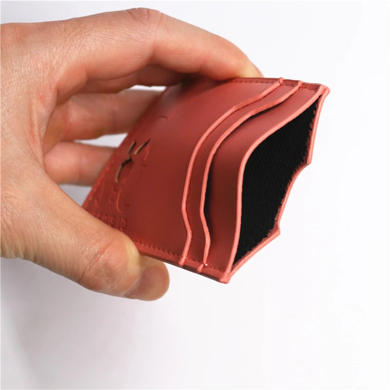A hand holds a brown leather slim card holder wallet with a black lining.