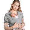 A woman wearing a knitted fabric multi-functional baby carrier holding a baby.