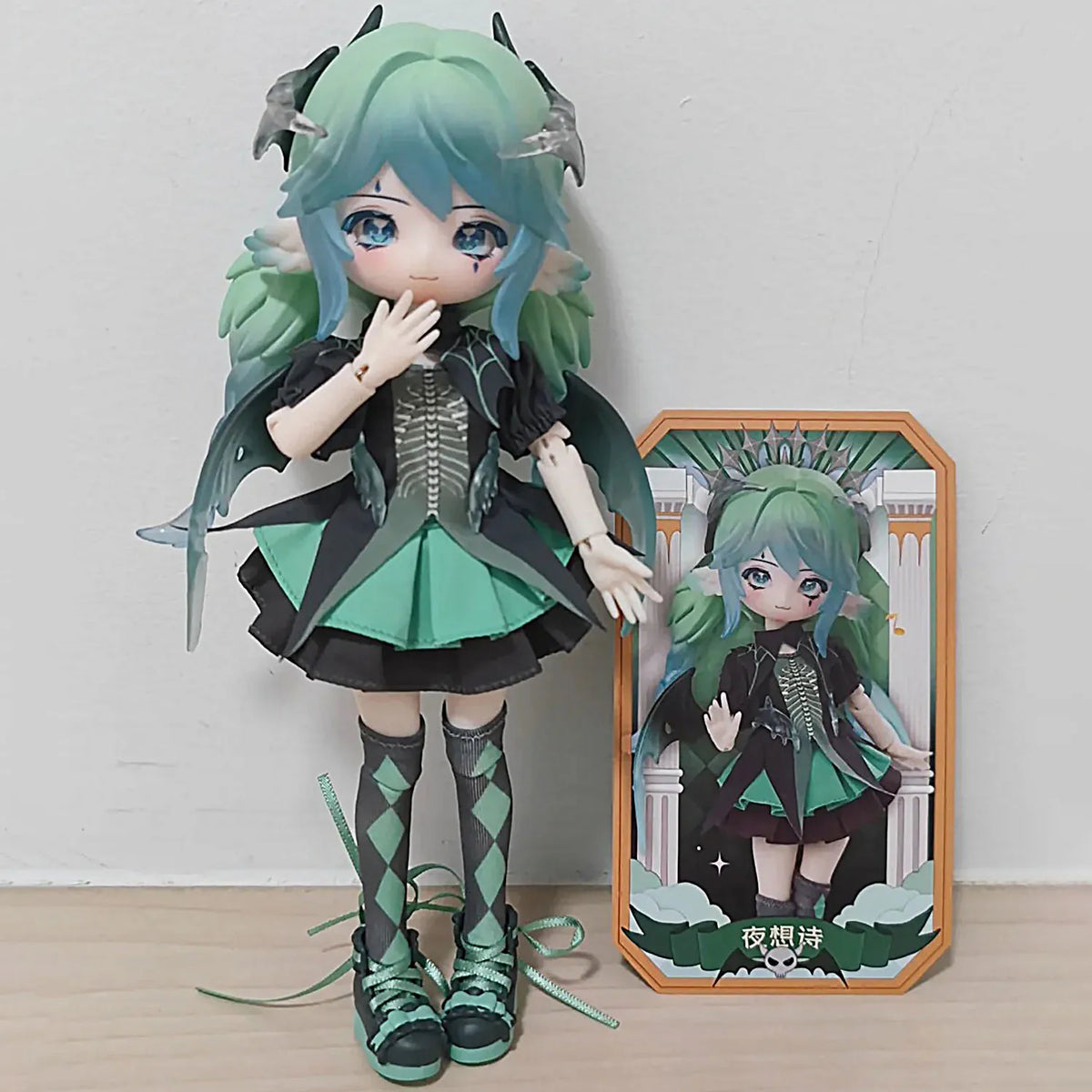 A detailed articulated doll of a female character with teal hair and green clothing displayed next to its packaging box.