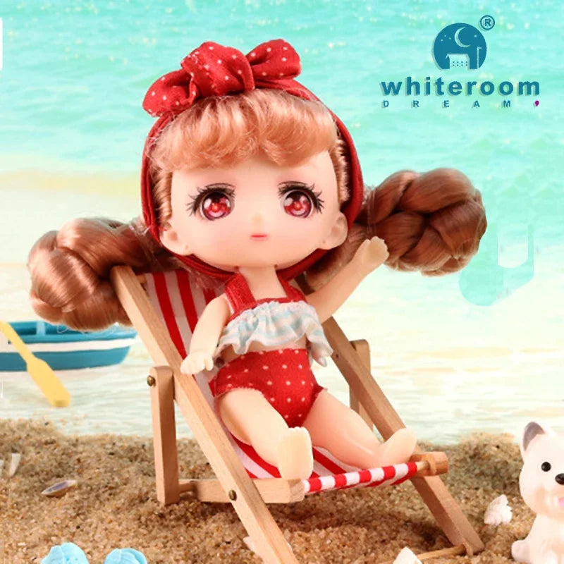 A small, rosy-cheeked doll with reddish hair is seated in a wooden deck chair outdoors.