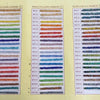 A display of various colored glass rice beads in different sizes, organized by color and type.
