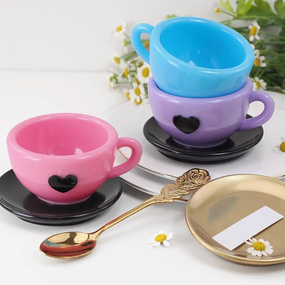 Trois tasses en silicone en forme de cœur bleu, violet et rose avec une cuillère et une assiette dorées