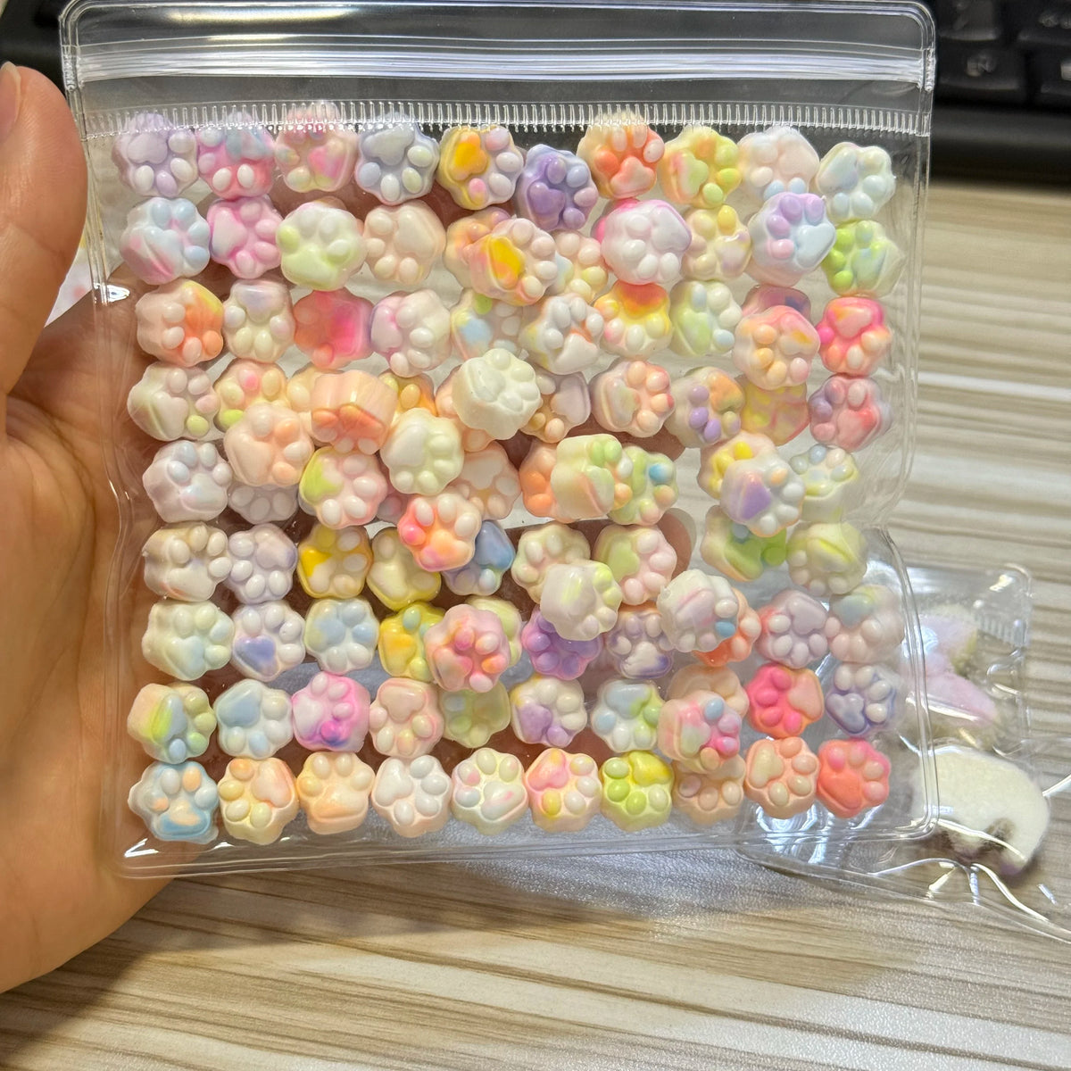 A clear plastic bag filled with numerous pastel-colored squishy toys shaped like cat paws.