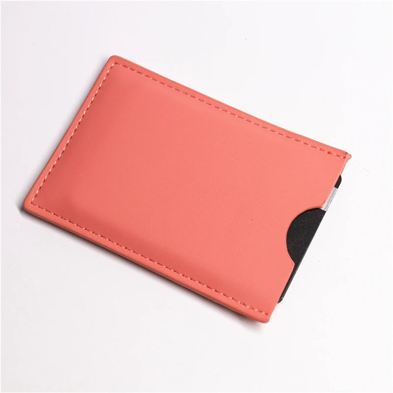 A slim card holder wallet in a coral pink color with a black sleeve visible.