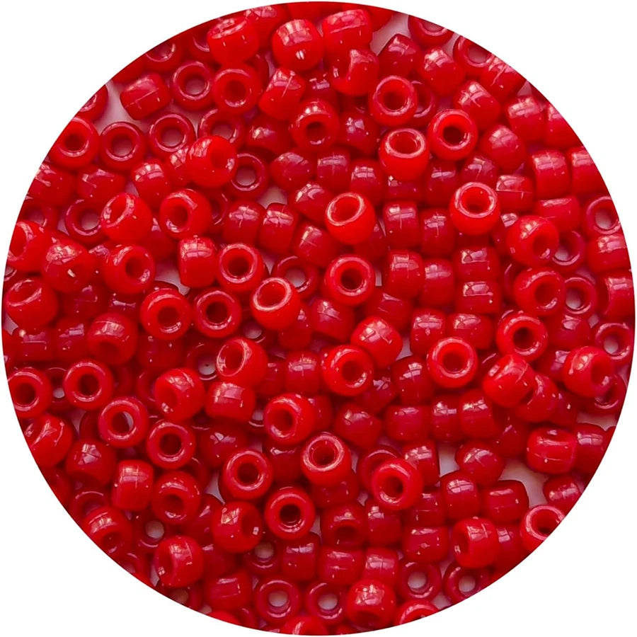 A close-up view of small, bright red pony beads scattered on a white background.